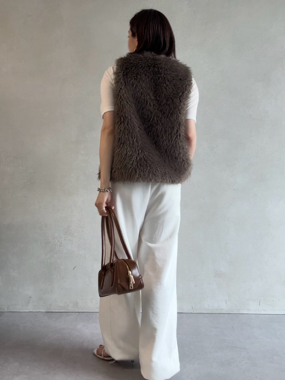 ホワイト系のスウェットパンツ、グレー系のベスト、ブラウン系のショルダーバッグを着用したレディースの秋コーディネートの3枚目の写真