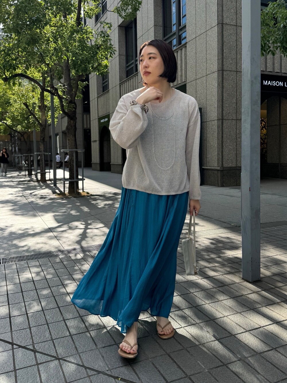 ブルー系のワンピース、ベージュ系のニット/セーター、ホワイト系のショルダーバッグを着用したレディースの夏コーディネートの3枚目の写真