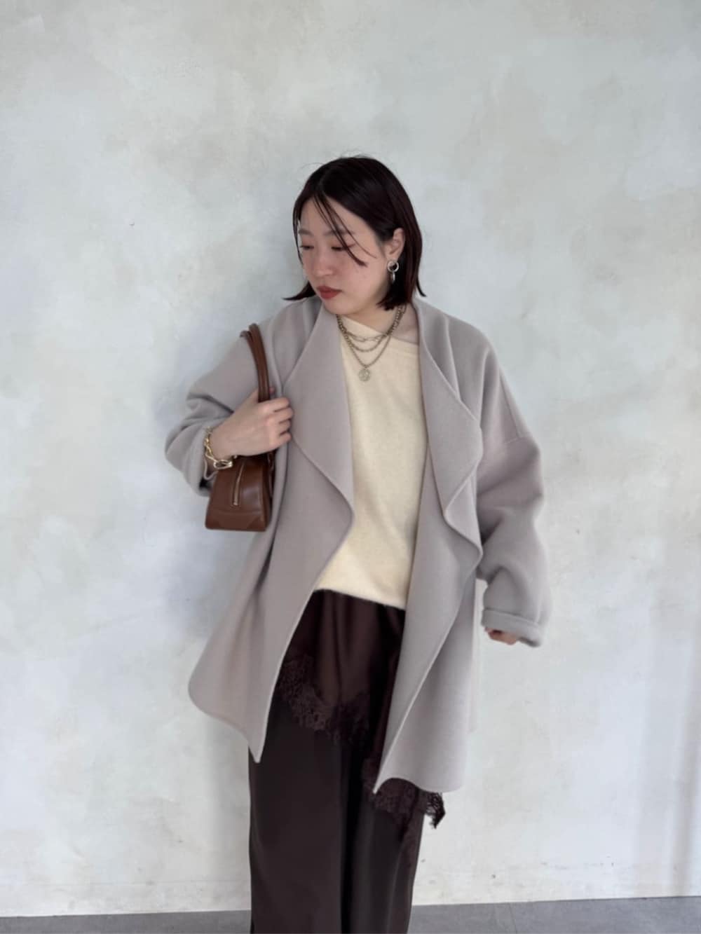 ブラウン系のスラックス、ベージュ系のその他アウター、ブラウン系のキャミソールを着用したレディースの冬コーディネートの4枚目の写真