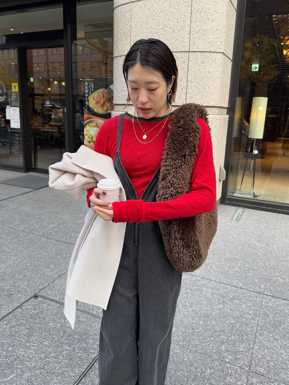 ブラック系のつなぎ/オールインワン、レッド系のニット/セーター、ブラック系のその他アウターを着用したレディースの冬コーディネートの8枚目の写真