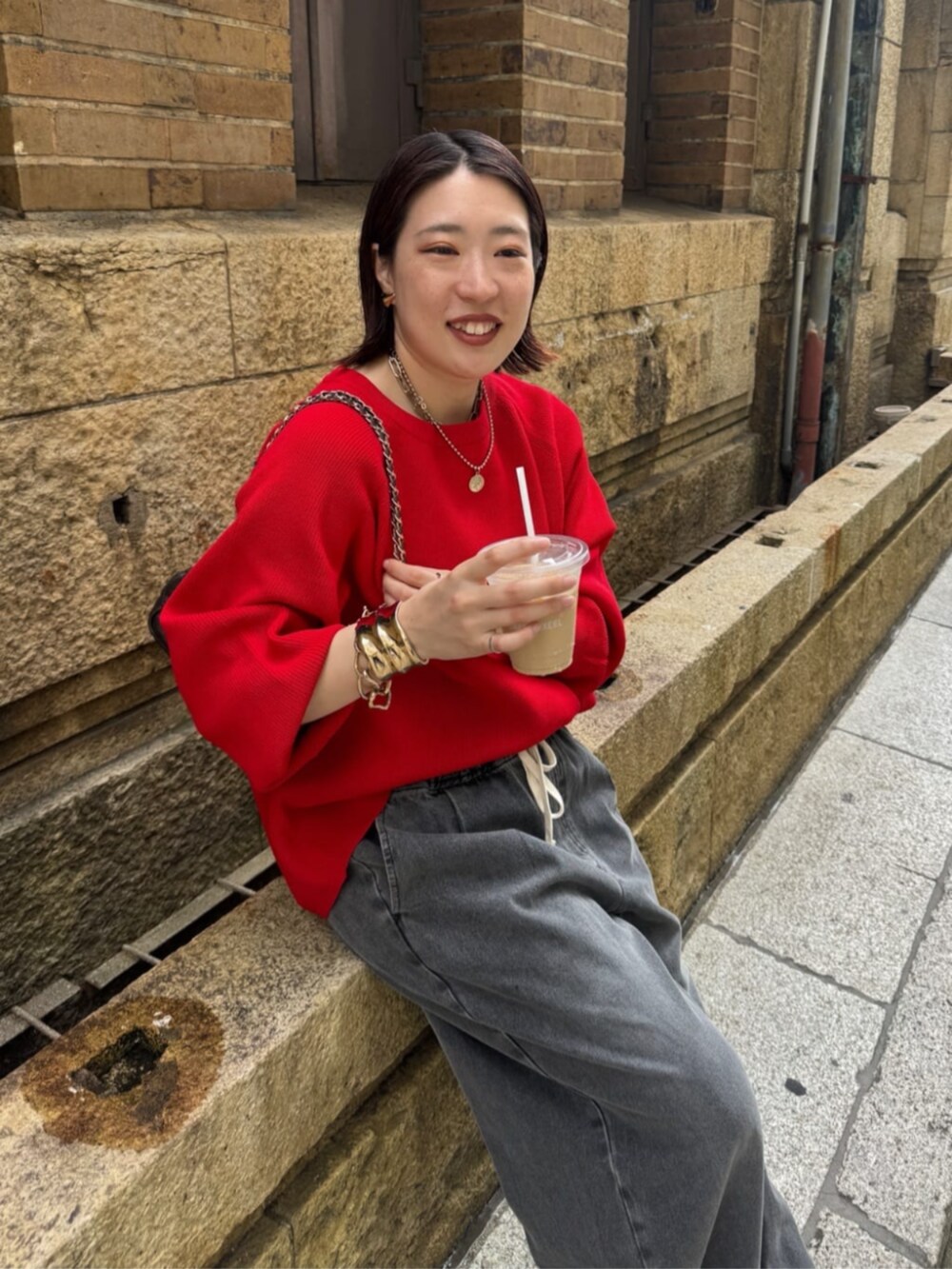 ブラック系のデニムパンツ、ブラウン系のショルダーバッグ、レッド系のニット/セーターを着用したレディースの夏コーディネートの9枚目の写真