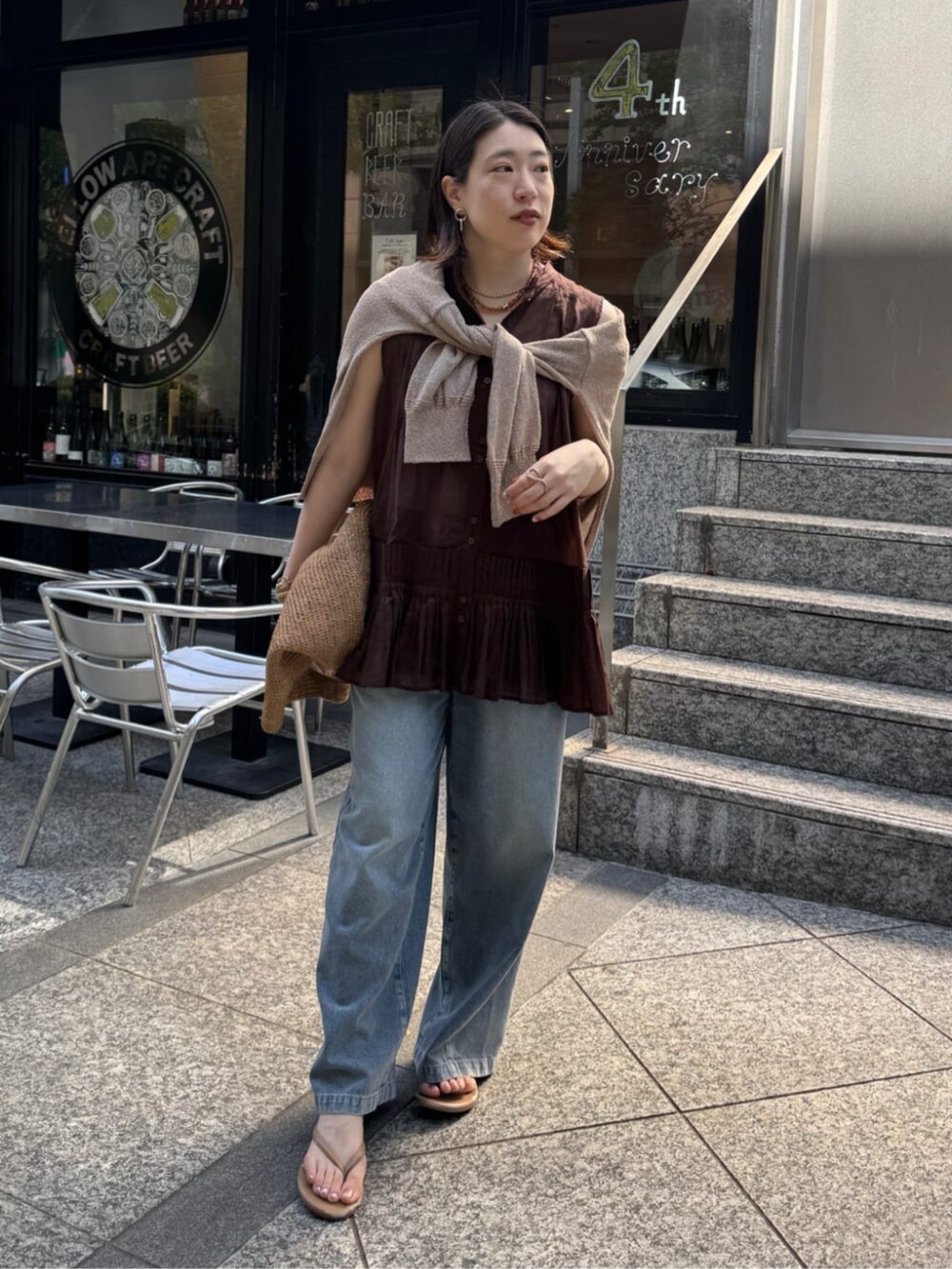 ブルー系のデニムパンツ、ベージュ系のカーディガン/ボレロ、ブラウン系のシャツ/ブラウスを着用したレディースの春コーディネートの2枚目の写真