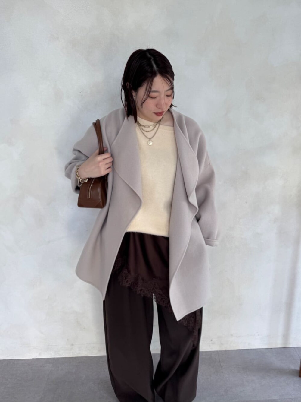 ブラウン系のスラックス、ベージュ系のその他アウター、ブラウン系のキャミソールを着用したレディースの冬コーディネートの5枚目の写真