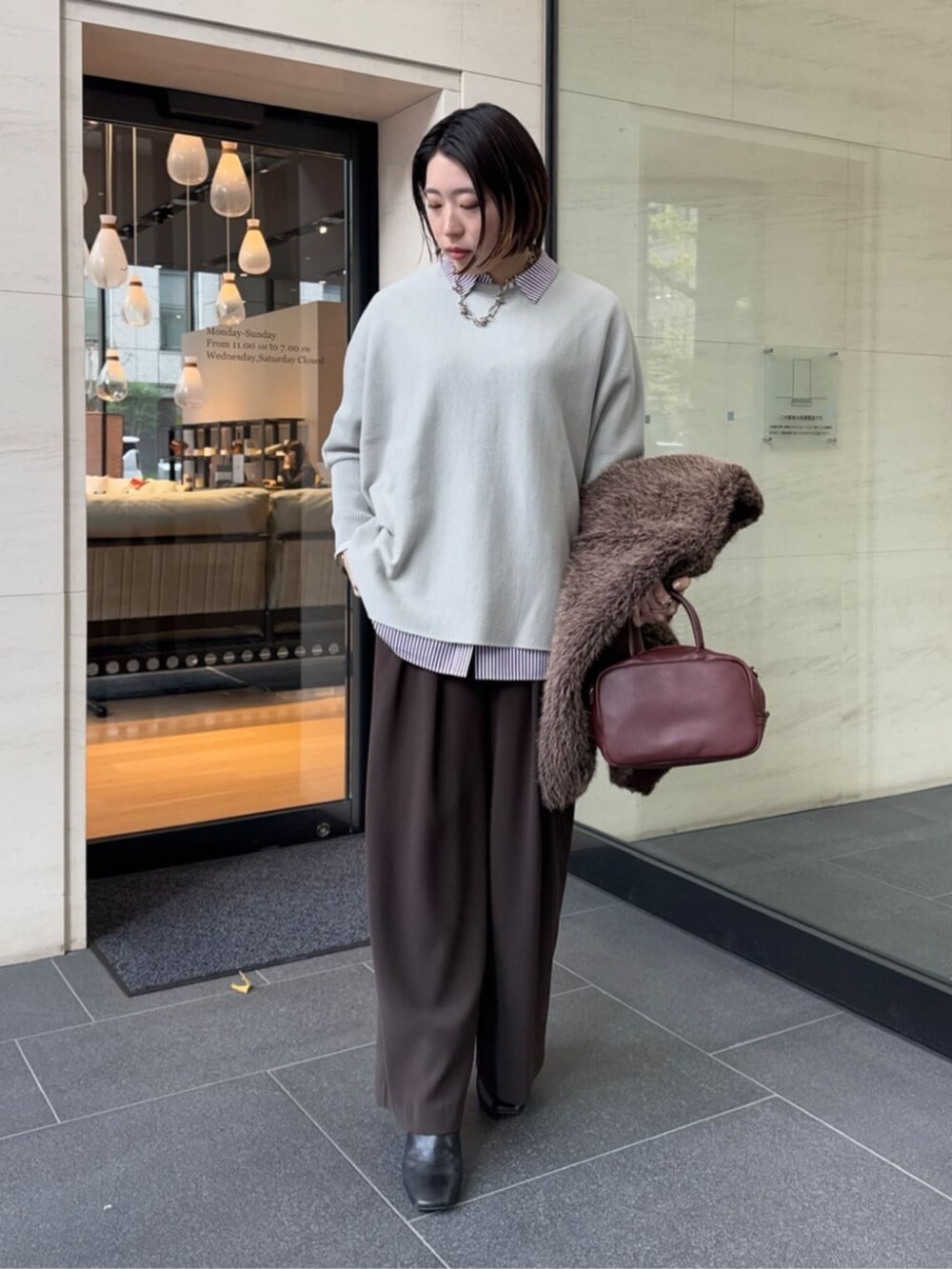 ブラウン系のスラックス、レッド系のシャツ/ブラウス、ブラウン系のショルダーバッグを着用したレディースの冬コーディネートの6枚目の写真