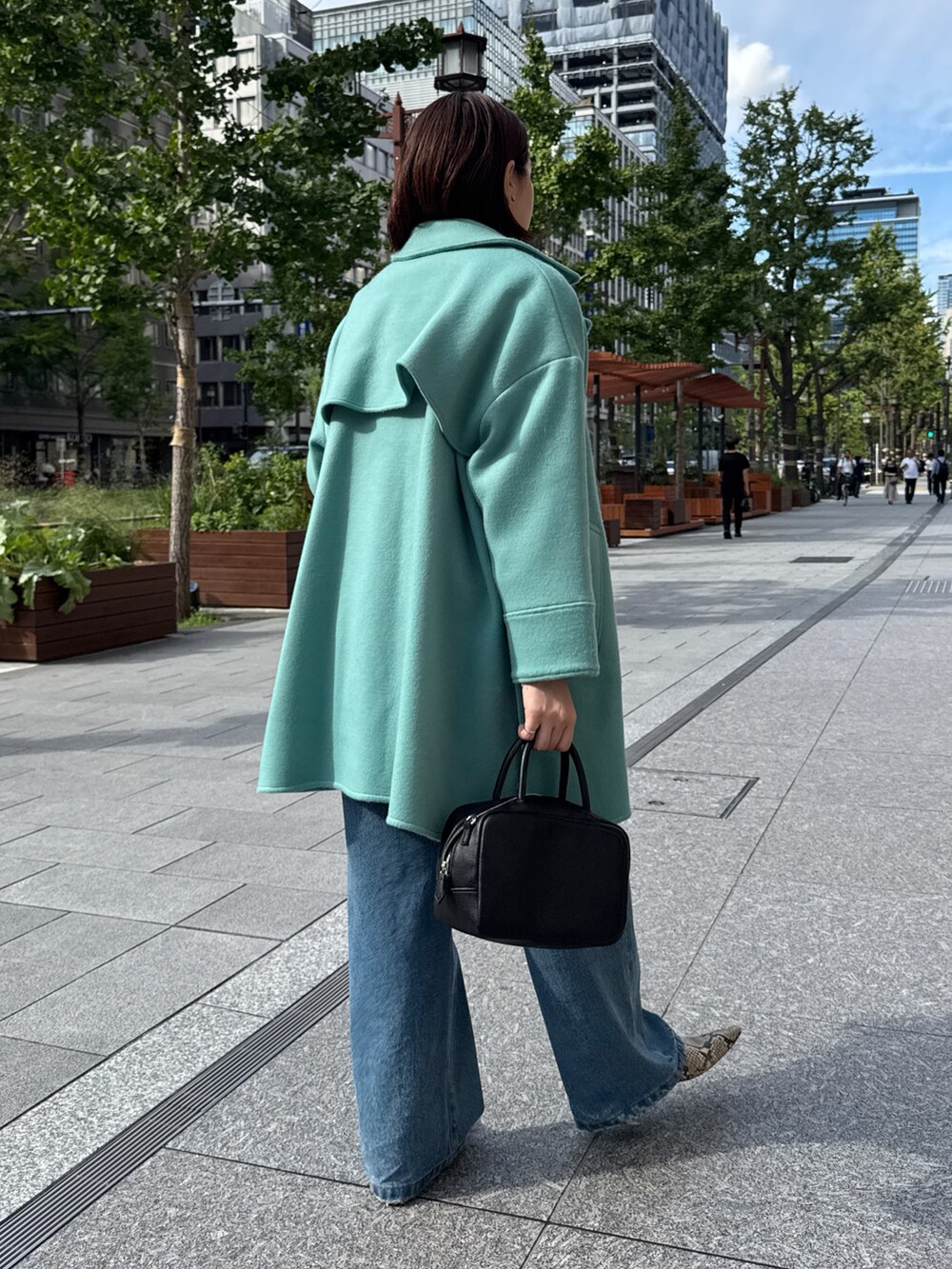 ベージュ系のニット/セーター、グリーン系のその他アウター、ブルー系のデニムパンツを着用したレディースの秋コーディネートの5枚目の写真