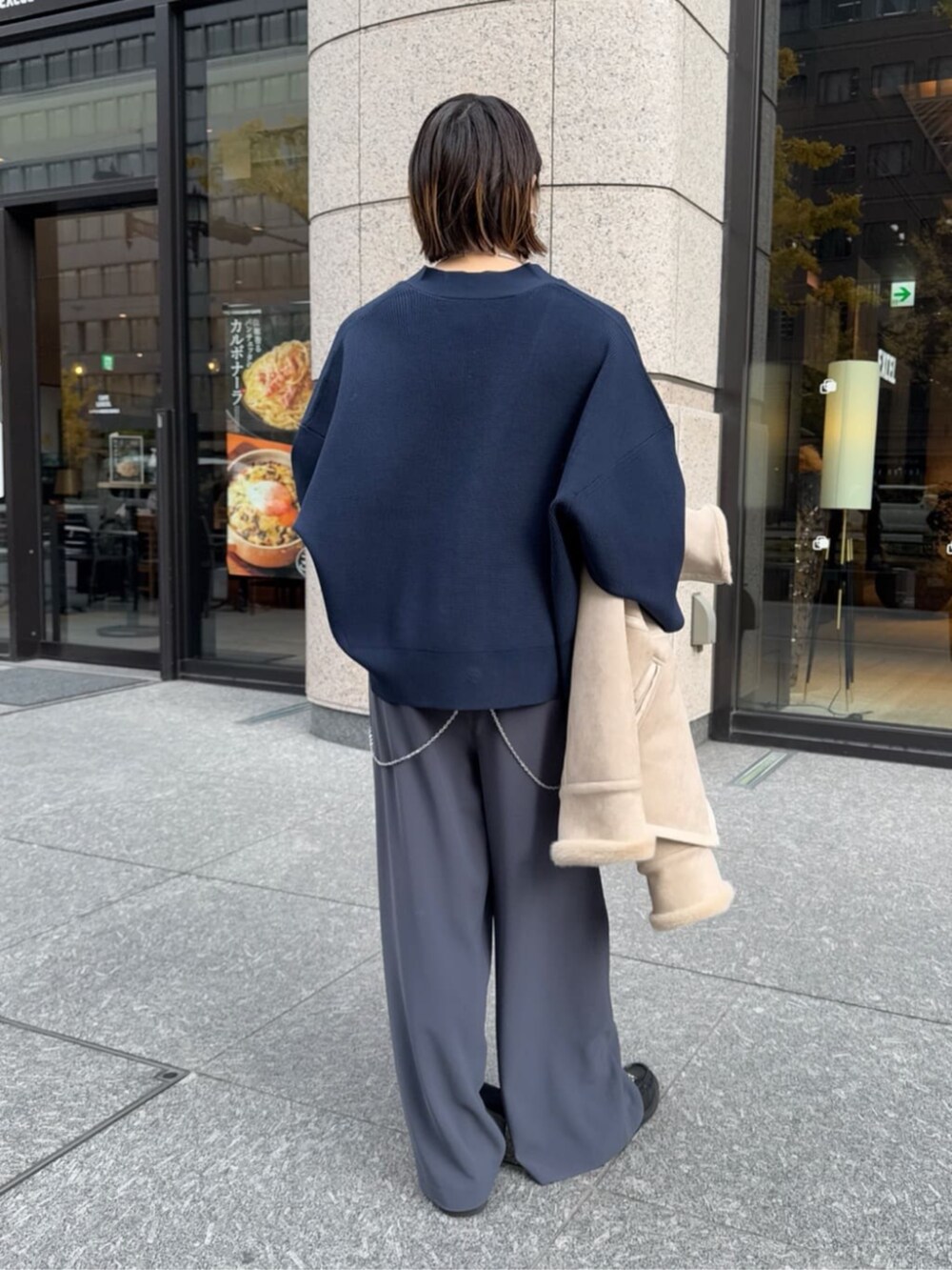 グレー系のスラックス、ブラック系のショルダーバッグ、ベージュ系のその他アウターを着用したレディースの冬コーディネートの2枚目の写真