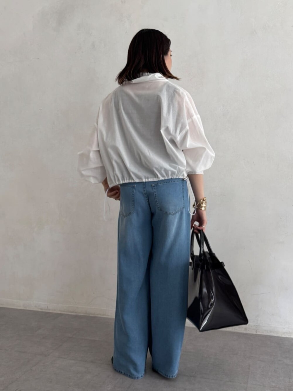 ブラック系のショルダーバッグ、ブルー系のデニムパンツ、ブラウン系のニット/セーターを着用したレディースの夏コーディネートの4枚目の写真