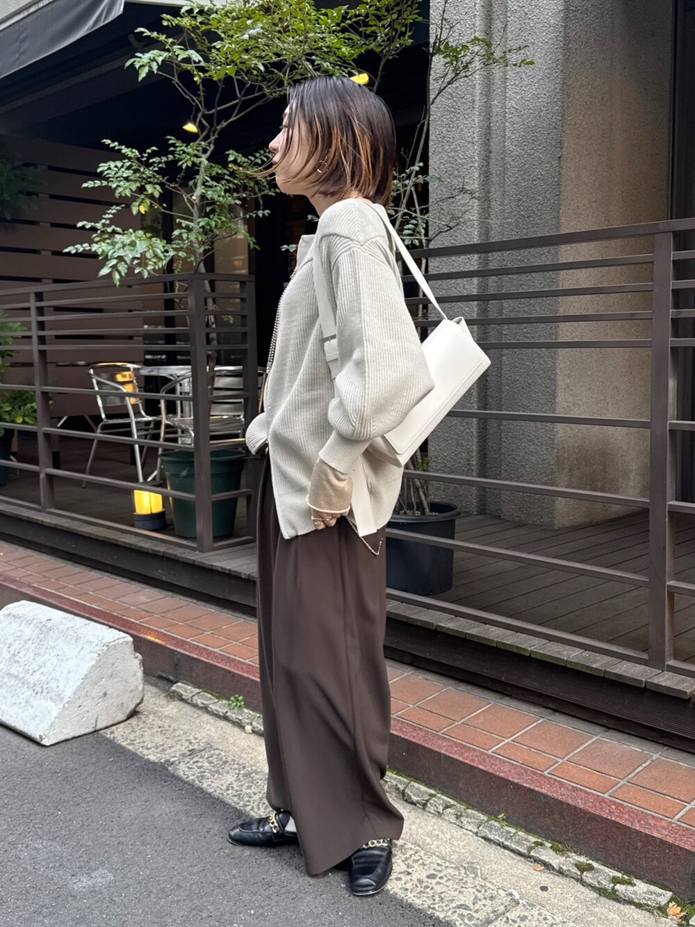 グレー系のニット/セーター、ブラウン系のスラックス、ゴールド系のTシャツ/カットソーを着用したレディースの冬コーディネートの3枚目の写真