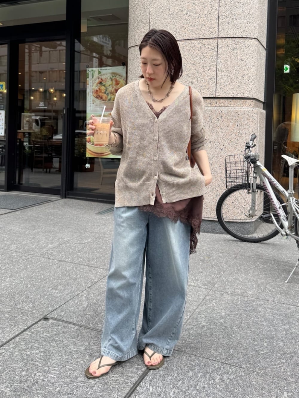 ブルー系のデニムパンツ、ブラウン系のキャミソール、ベージュ系のカーディガン/ボレロを着用したレディースの春コーディネートの5枚目の写真