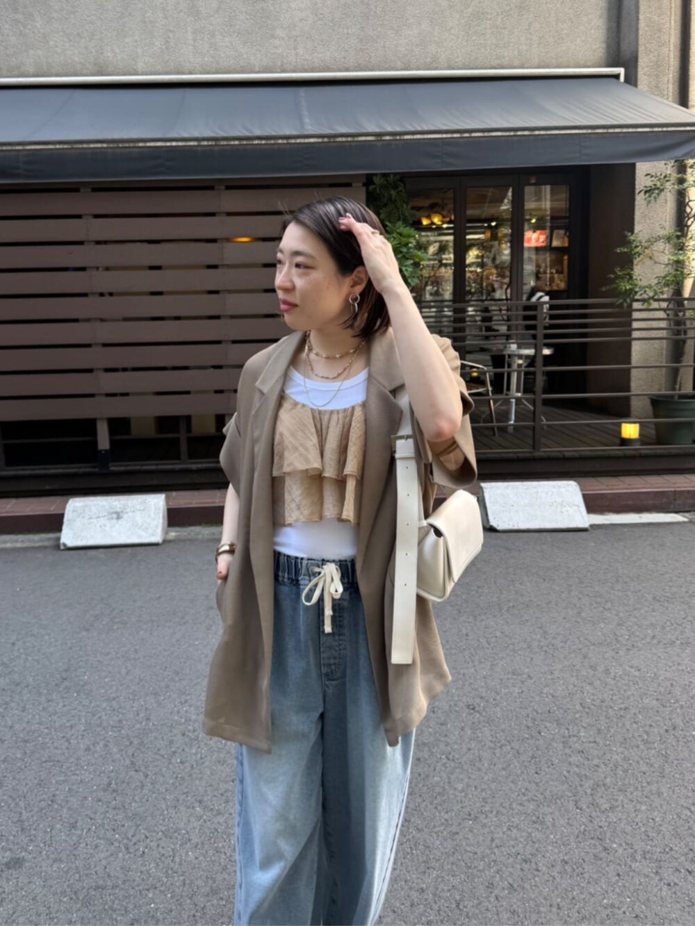 ホワイト系のショルダーバッグ、ブルー系のデニムパンツ、ブラウン系のテーラードジャケットを着用したレディースの春コーディネートの8枚目の写真