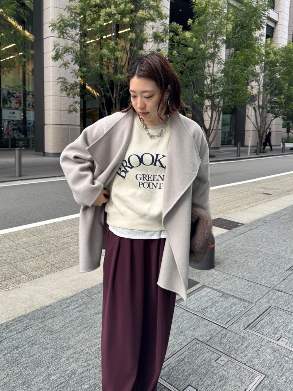 レッド系のスラックス、ベージュ系のその他アウター、ホワイト系のニット/セーターを着用したレディースの秋コーディネートの2枚目の写真