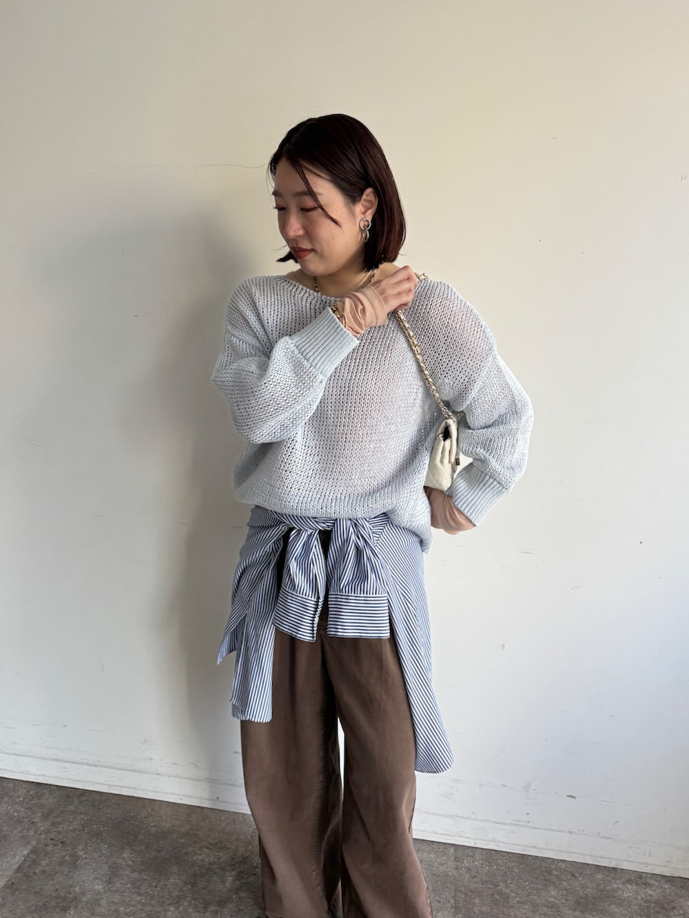 ブルー系のニット/セーター、ピンク系のTシャツ/カットソー、ブラウン系のデニムパンツを着用したレディースの冬コーディネートの4枚目の写真