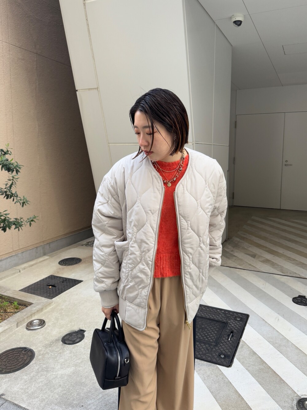 ベージュ系のその他パンツ、ホワイト系のその他アウター、オレンジ系のニット/セーターを着用したレディースの冬コーディネートの8枚目の写真