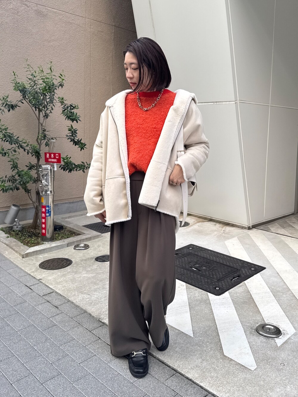 ブラウン系のスラックス、ホワイト系のその他アウター、ホワイト系のショルダーバッグを着用したレディースの秋コーディネートの3枚目の写真