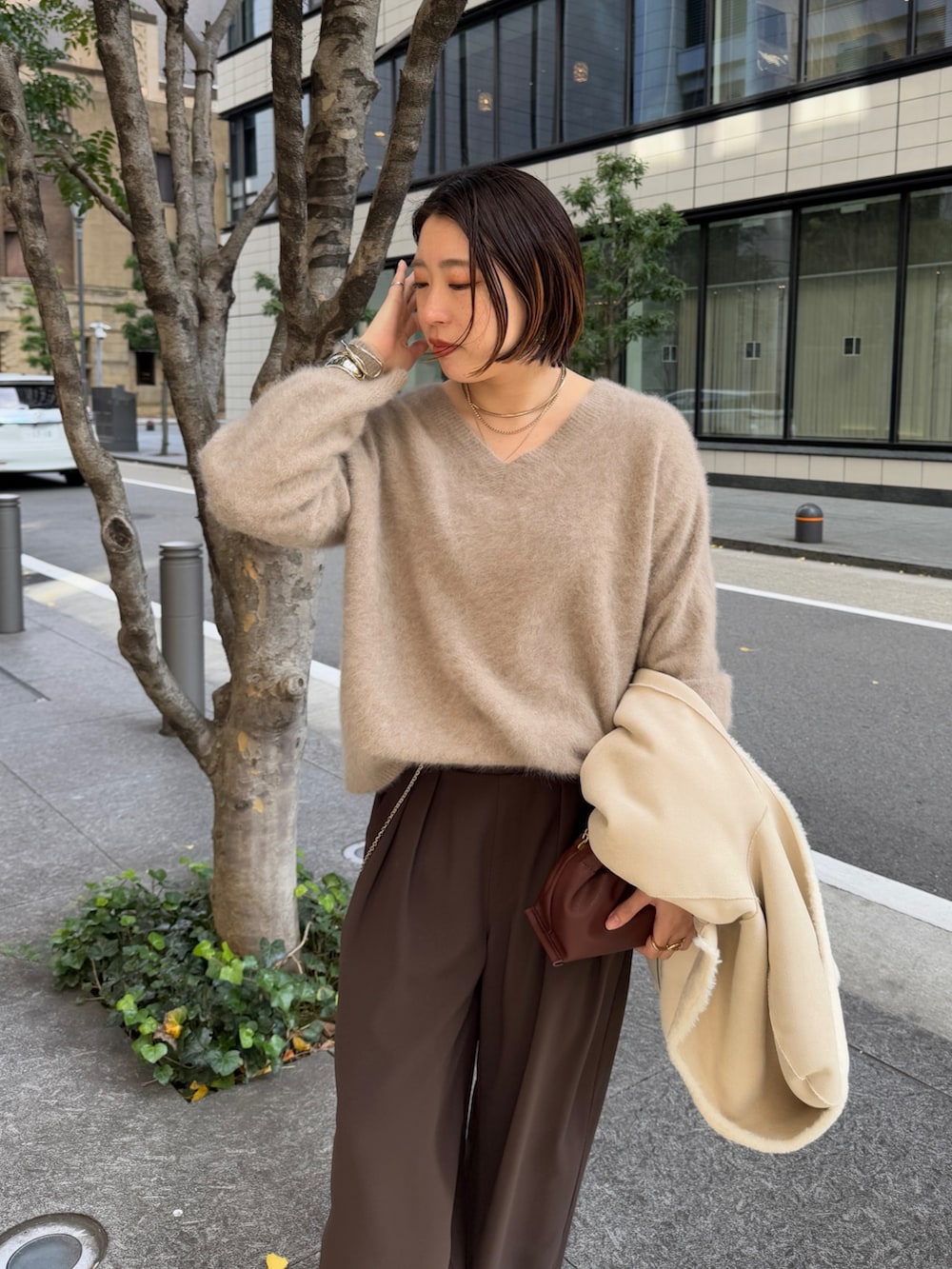 ブラウン系のスラックス、ブラウン系のニット/セーター、ホワイト系のその他アウターを着用したレディースの冬コーディネートの9枚目の写真