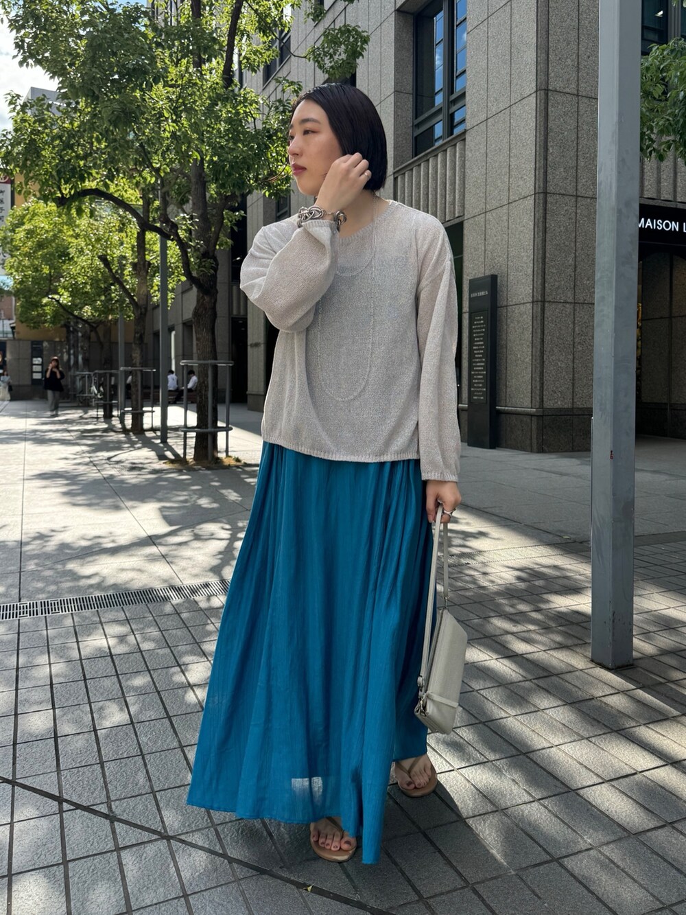 ブルー系のワンピース、ベージュ系のニット/セーター、ホワイト系のショルダーバッグを着用したレディースの夏コーディネートの5枚目の写真