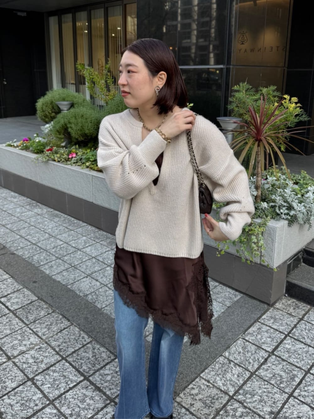 ブラウン系のキャミソール、ブルー系のデニムパンツ、ホワイト系のニット/セーターを着用したレディースの冬コーディネートの5枚目の写真