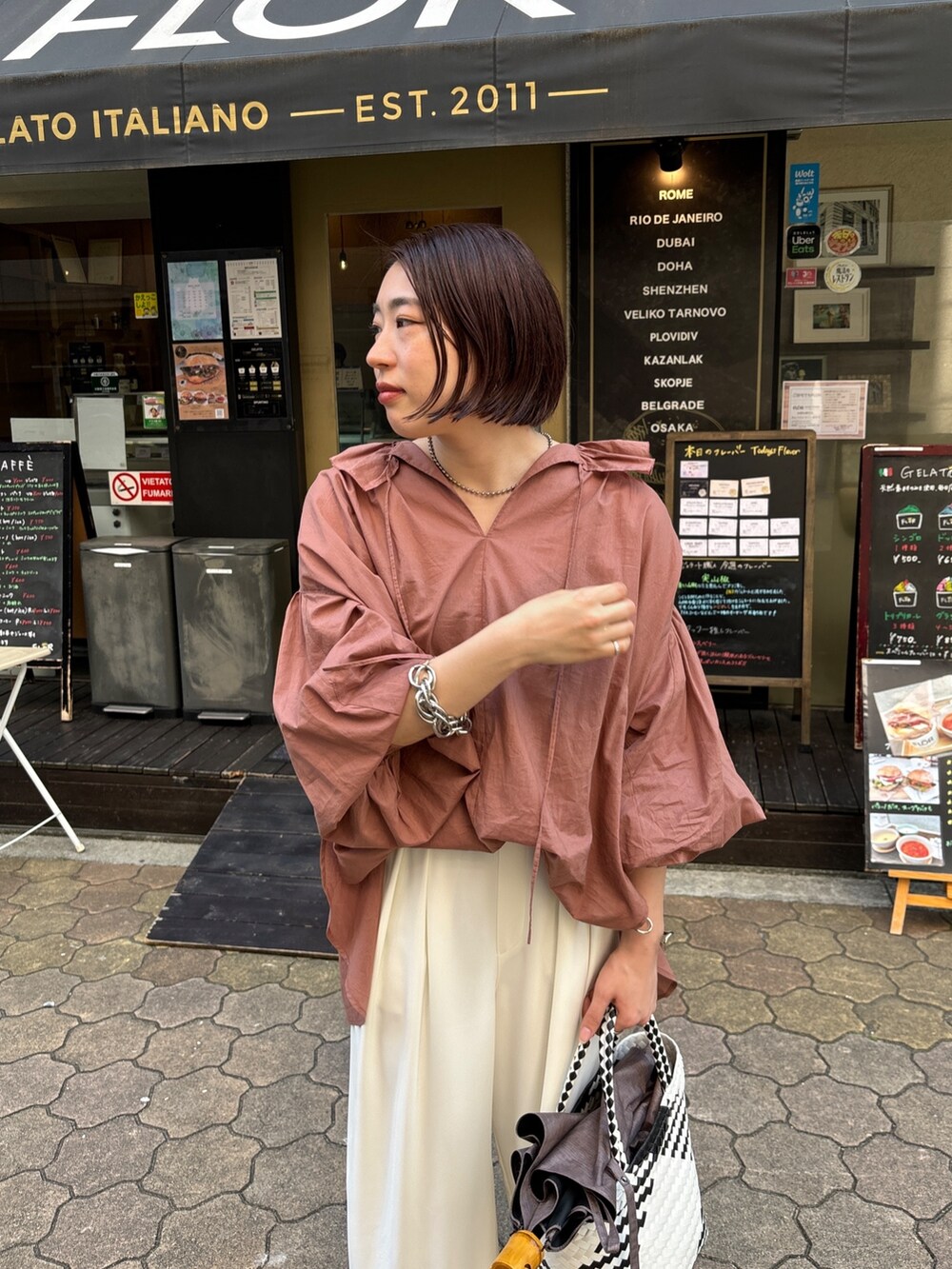 ホワイト系のスラックス、ブラウン系のシャツ/ブラウス、ホワイト系のかごバッグを着用したレディースの夏コーディネートの6枚目の写真