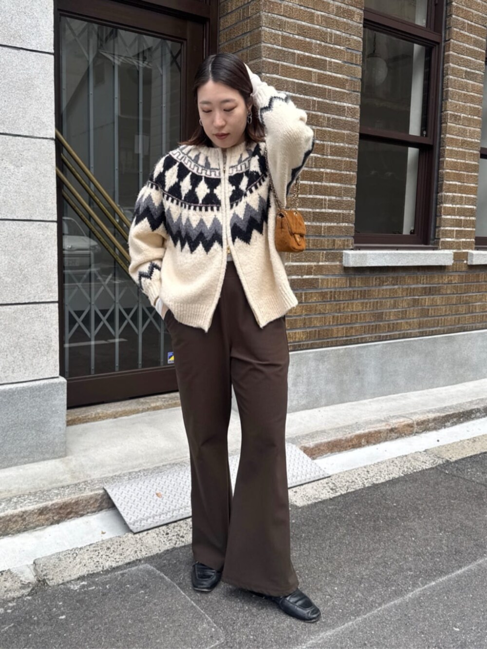 イエロー系のショルダーバッグ、ホワイト系のカーディガン/ボレロ、ブラウン系のその他パンツを着用したレディースの冬コーディネートの3枚目の写真