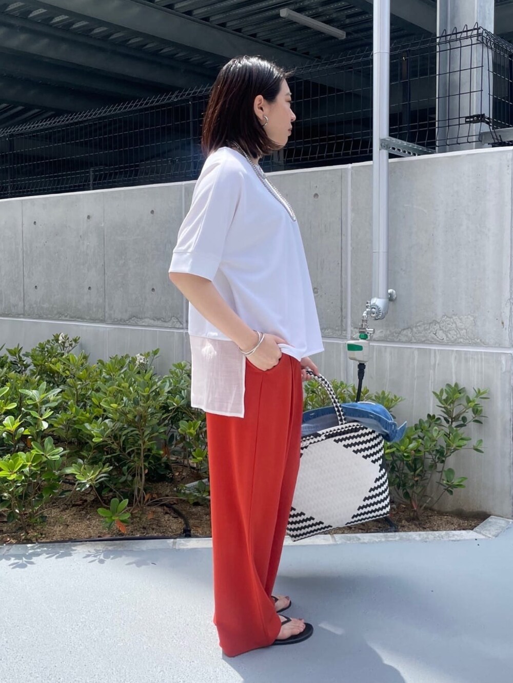 ホワイト系のシャツ/ブラウス、オレンジ系のスラックス、ホワイト系のかごバッグを着用したレディースの夏コーディネートの9枚目の写真