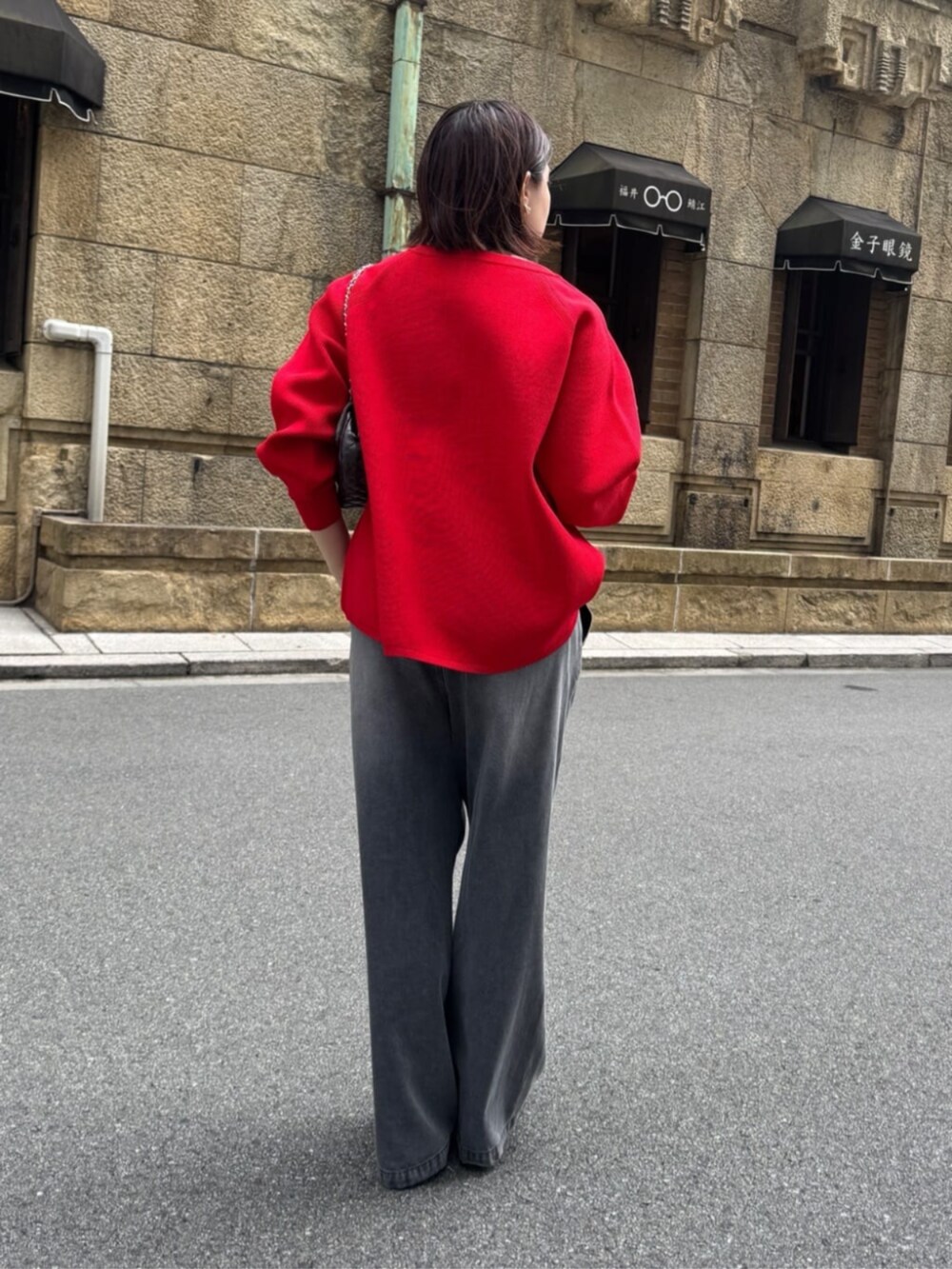 ブラック系のデニムパンツ、ブラウン系のショルダーバッグ、レッド系のニット/セーターを着用したレディースの夏コーディネートの5枚目の写真