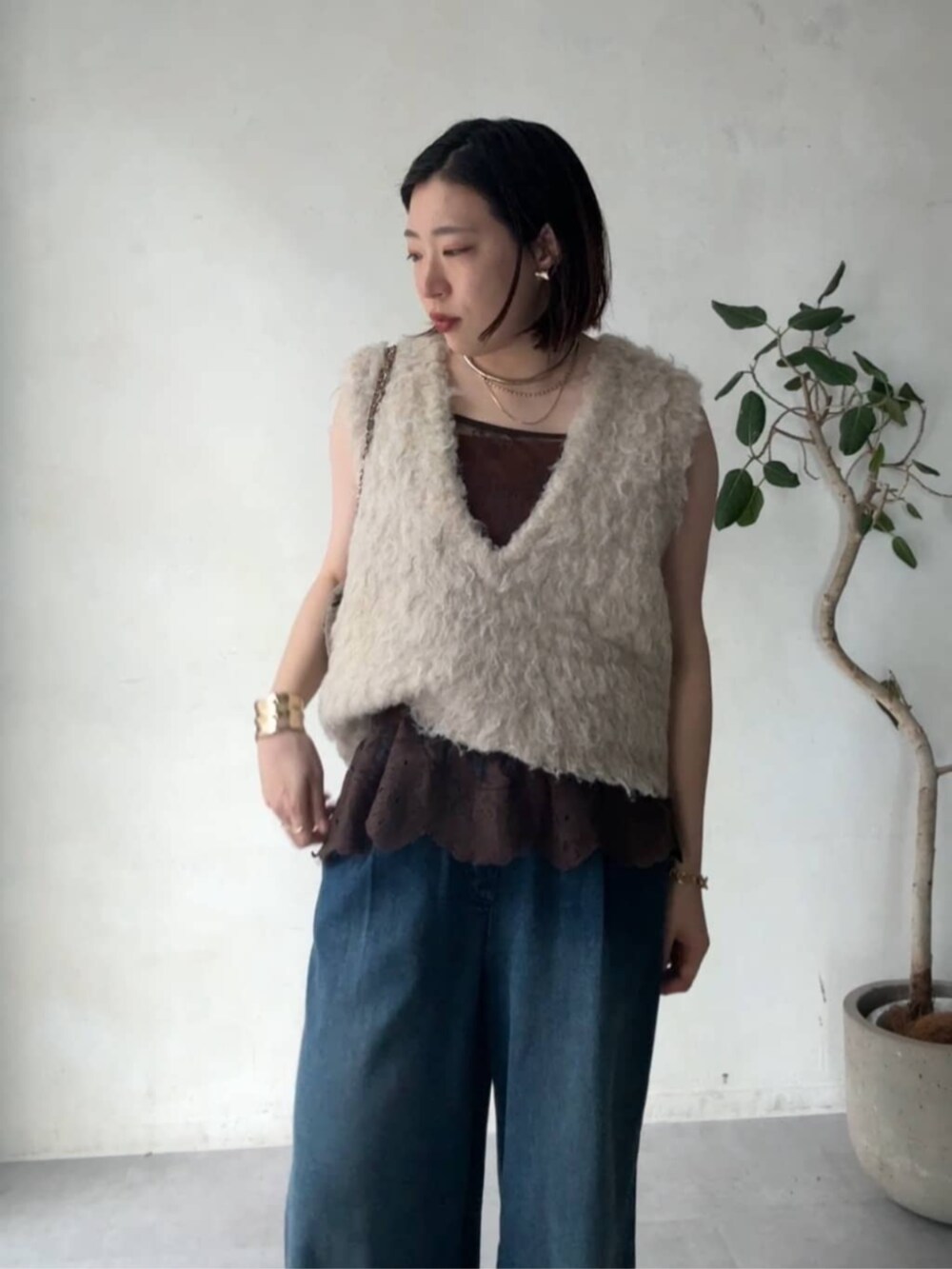 グレー系のショルダーバッグ、ベージュ系のニット/セーター、ブルー系のデニムパンツを着用したレディースの秋コーディネートの6枚目の写真