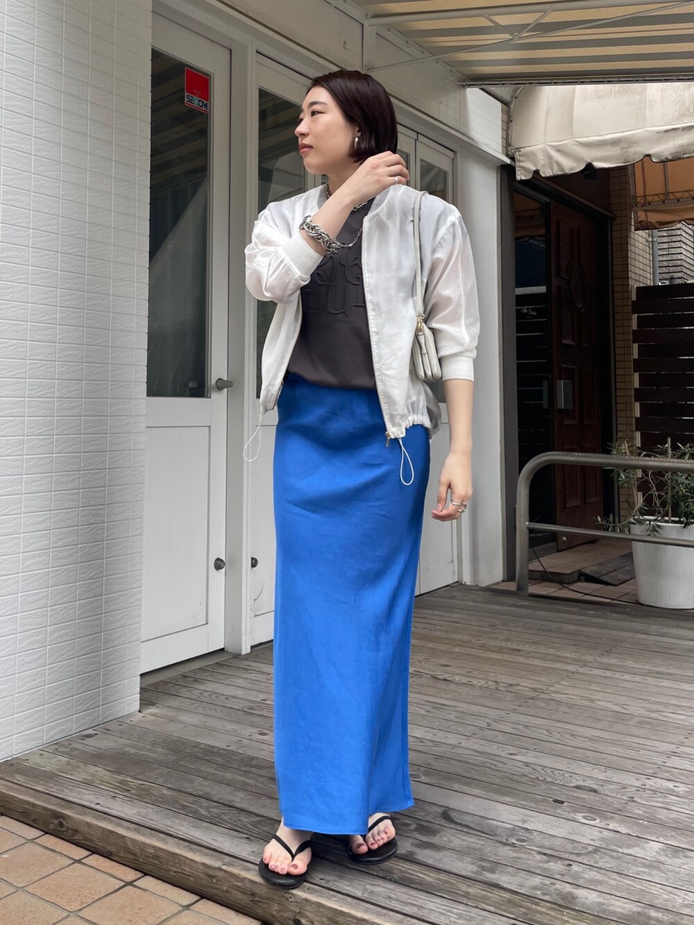 ブルー系のスカート、グレー系のTシャツ/カットソー、ホワイト系のブルゾンを着用したレディースの春コーディネートの4枚目の写真