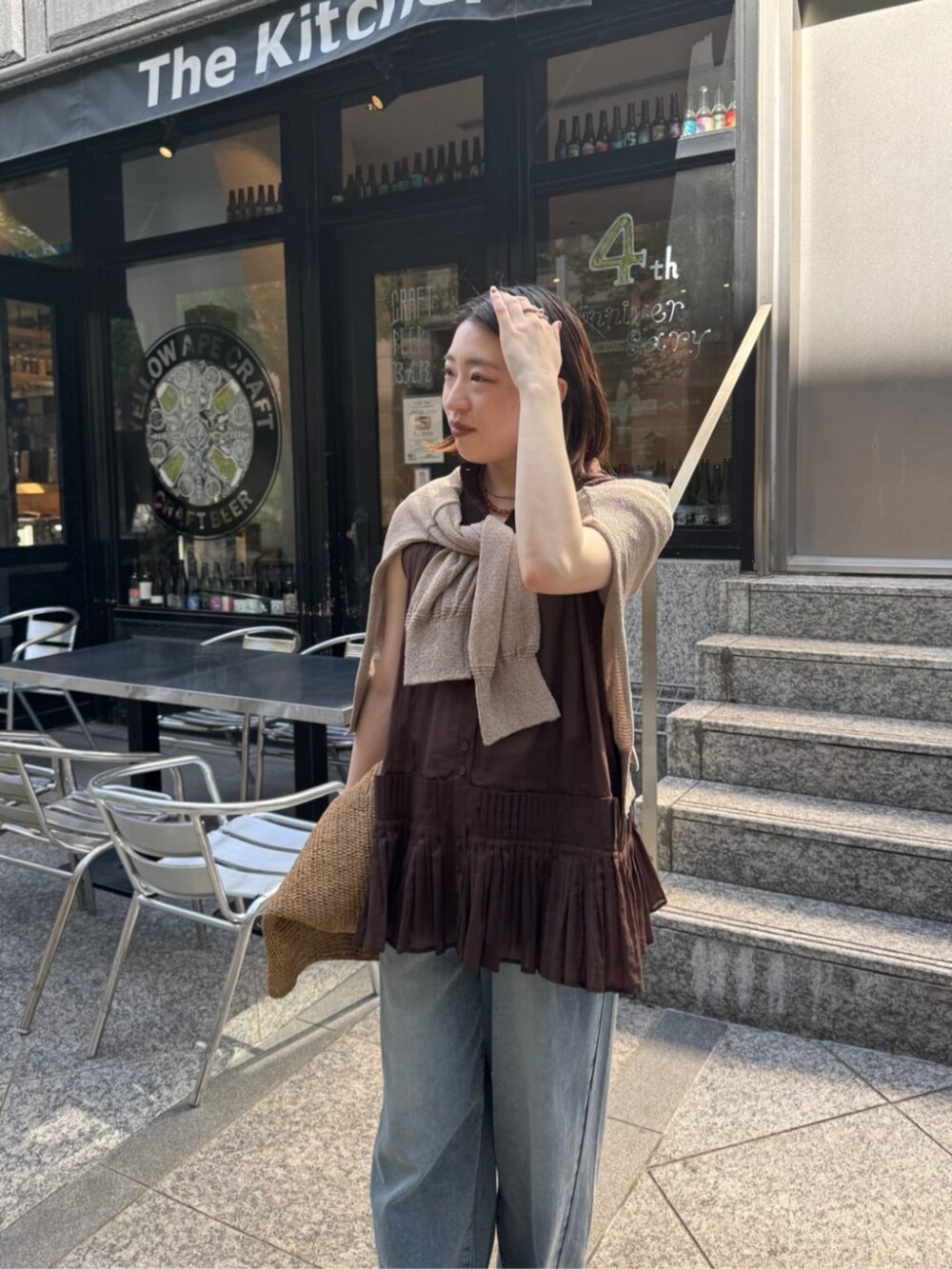 ブルー系のデニムパンツ、ベージュ系のカーディガン/ボレロ、ブラウン系のシャツ/ブラウスを着用したレディースの春コーディネートの5枚目の写真