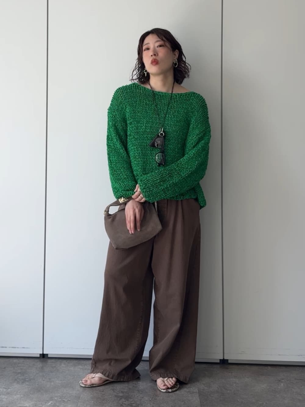 グリーン系のニット/セーター、ブラウン系のデニムパンツ、ブラウン系のネックレスを着用したレディースの秋コーディネートの3枚目の写真
