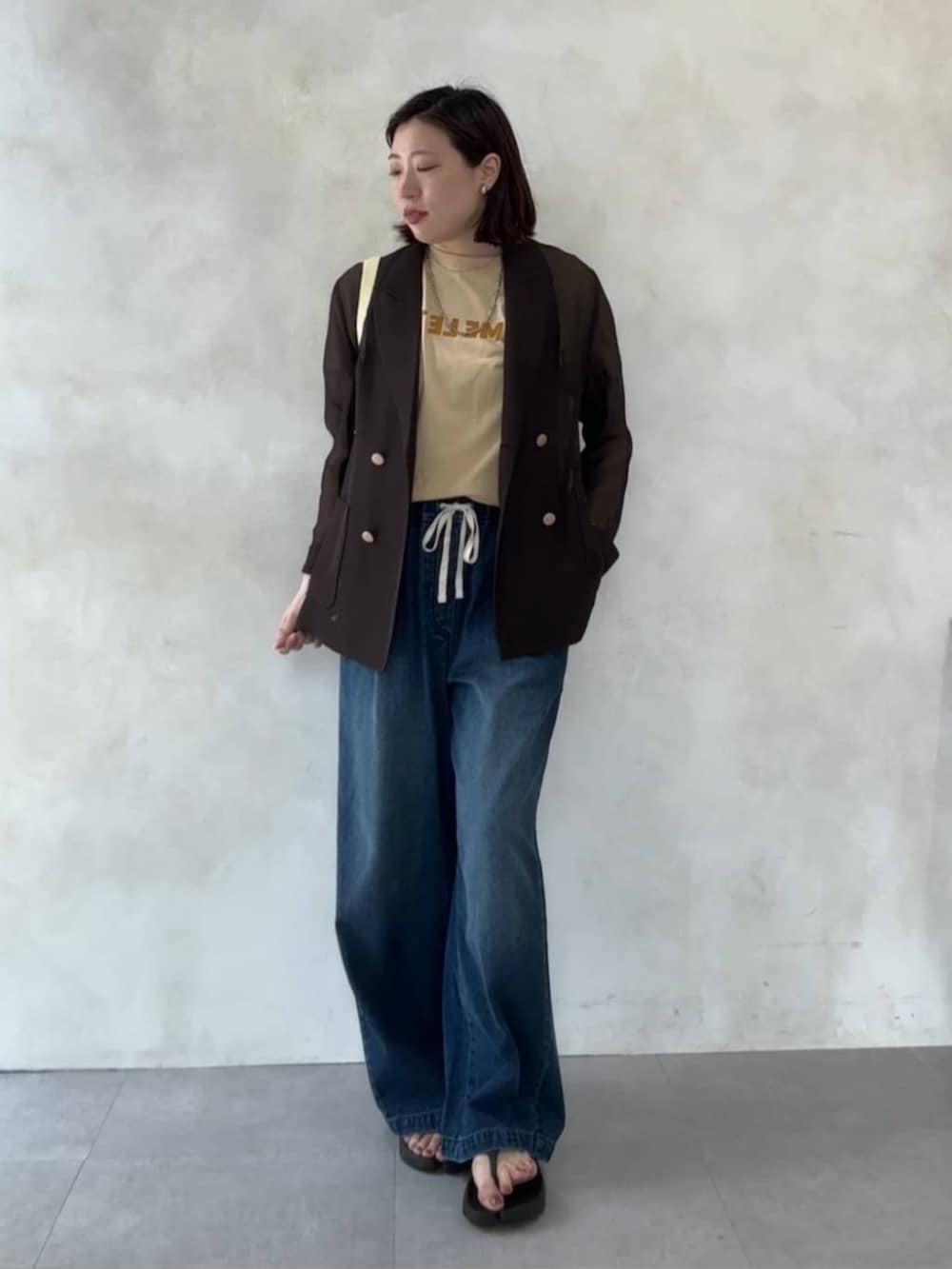 ブルー系のデニムパンツ、イエロー系のショルダーバッグ、ベージュ系のTシャツ/カットソーを着用したレディースの夏コーディネートの3枚目の写真