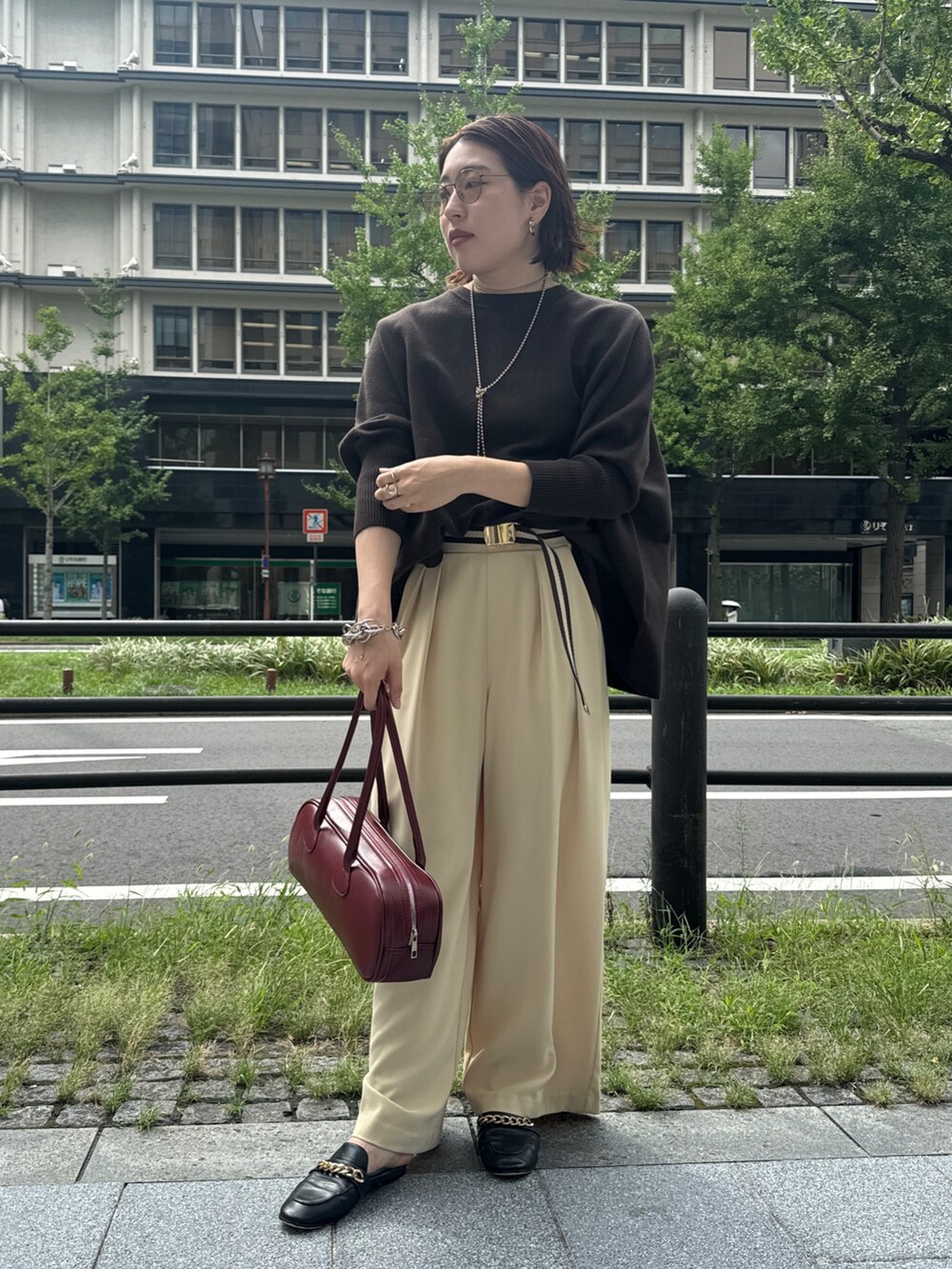 イエロー系のスラックス、ブラウン系のニット/セーター、ゴールド系のネックレスを着用したレディースの秋コーディネートの2枚目の写真