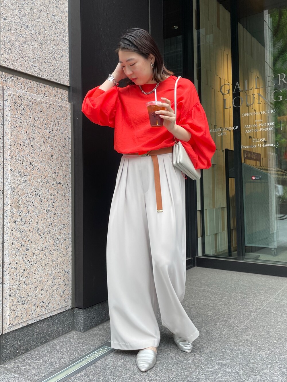 グレー系のスラックス、オレンジ系のシャツ/ブラウス、ホワイト系のショルダーバッグを着用したレディースの春コーディネートの3枚目の写真