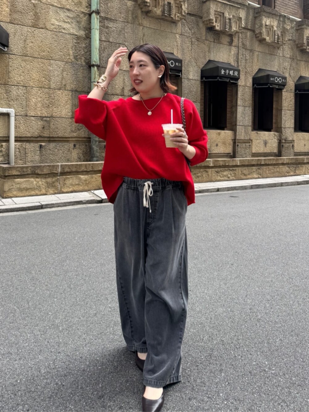 ブラック系のデニムパンツ、ブラウン系のショルダーバッグ、レッド系のニット/セーターを着用したレディースの夏コーディネートの4枚目の写真