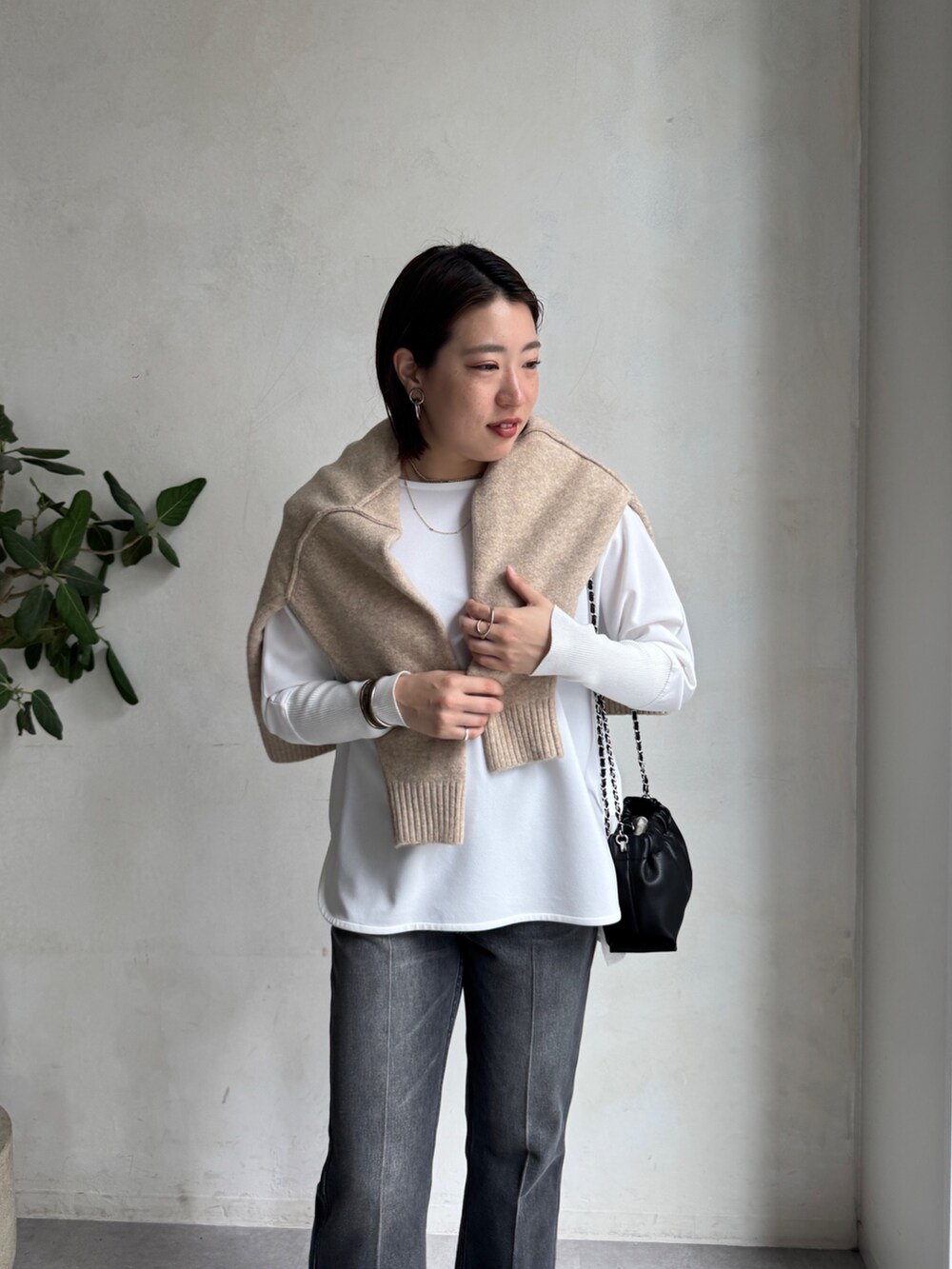 ブラック系のデニムパンツ、ベージュ系のニット/セーター、ホワイト系のTシャツ/カットソーを着用したレディースの秋コーディネートの9枚目の写真