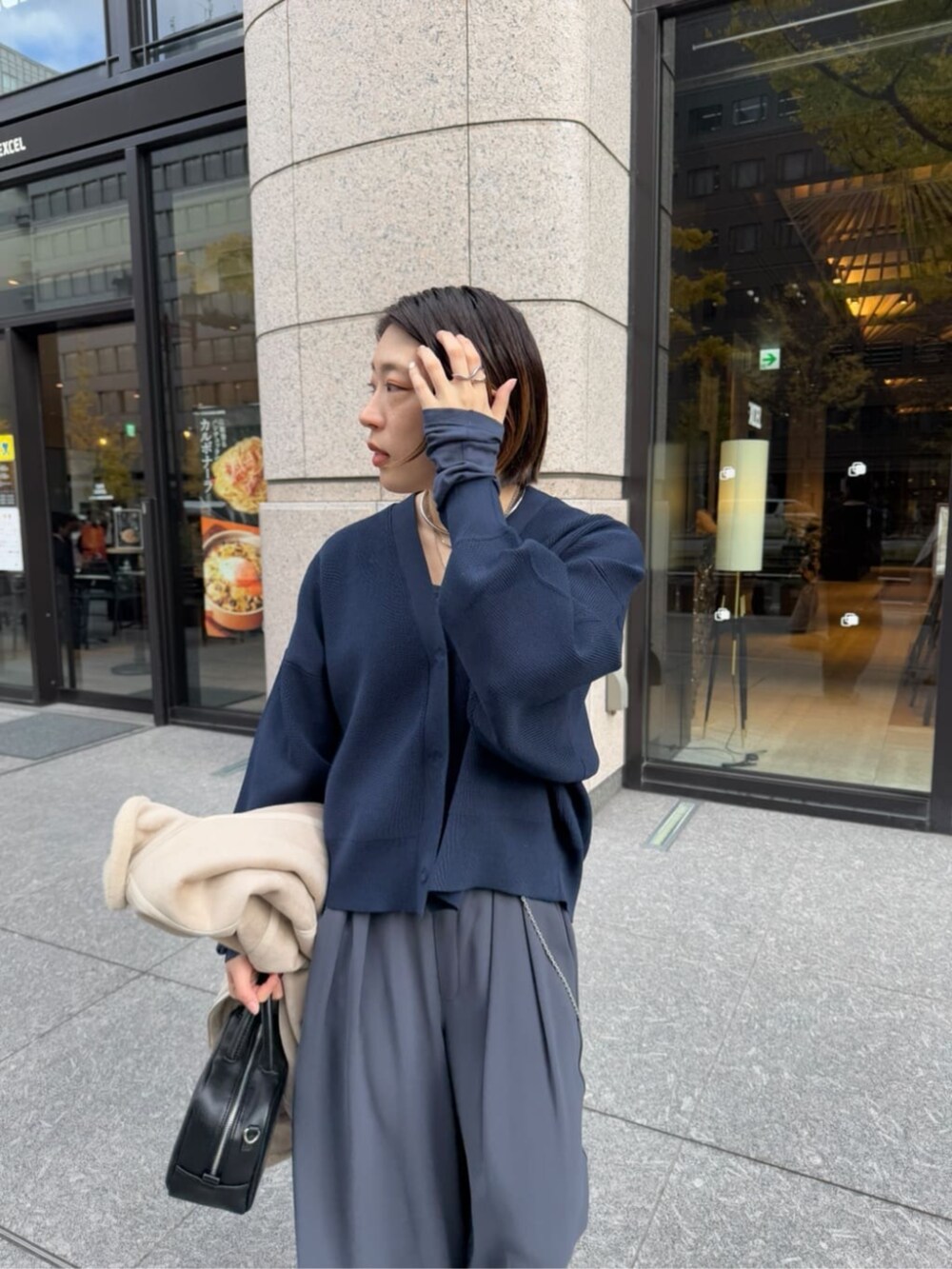 グレー系のスラックス、ブラック系のショルダーバッグ、ベージュ系のその他アウターを着用したレディースの冬コーディネートの8枚目の写真