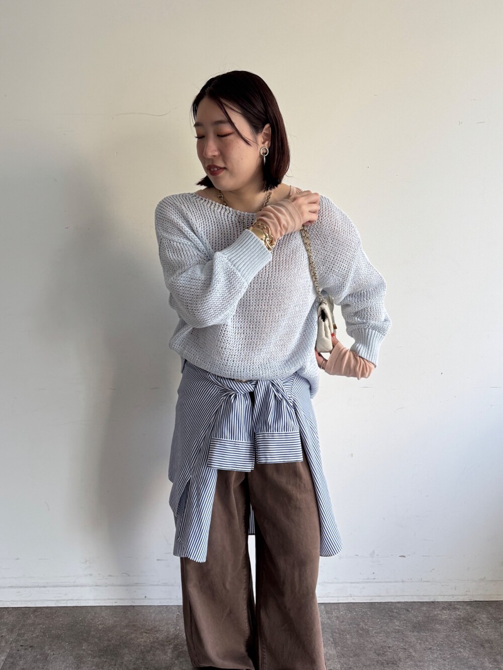 ブルー系のニット/セーター、ピンク系のTシャツ/カットソー、ブラウン系のデニムパンツを着用したレディースの冬コーディネートの3枚目の写真