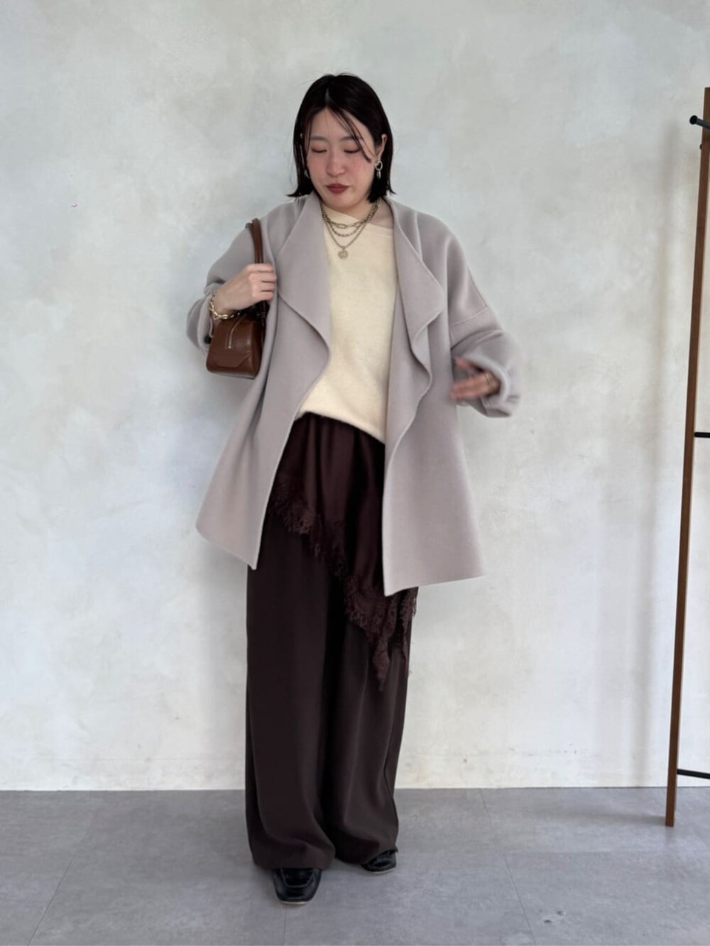 ブラウン系のスラックス、ベージュ系のその他アウター、ブラウン系のキャミソールを着用したレディースの冬コーディネートの3枚目の写真