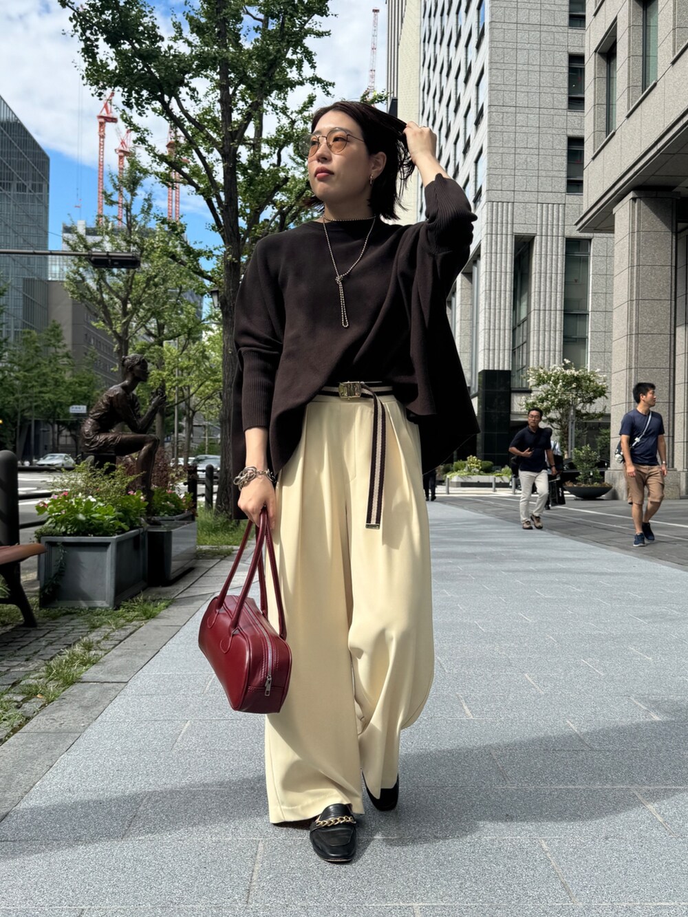 イエロー系のスラックス、ブラウン系のニット/セーター、ゴールド系のネックレスを着用したレディースの秋コーディネートの5枚目の写真