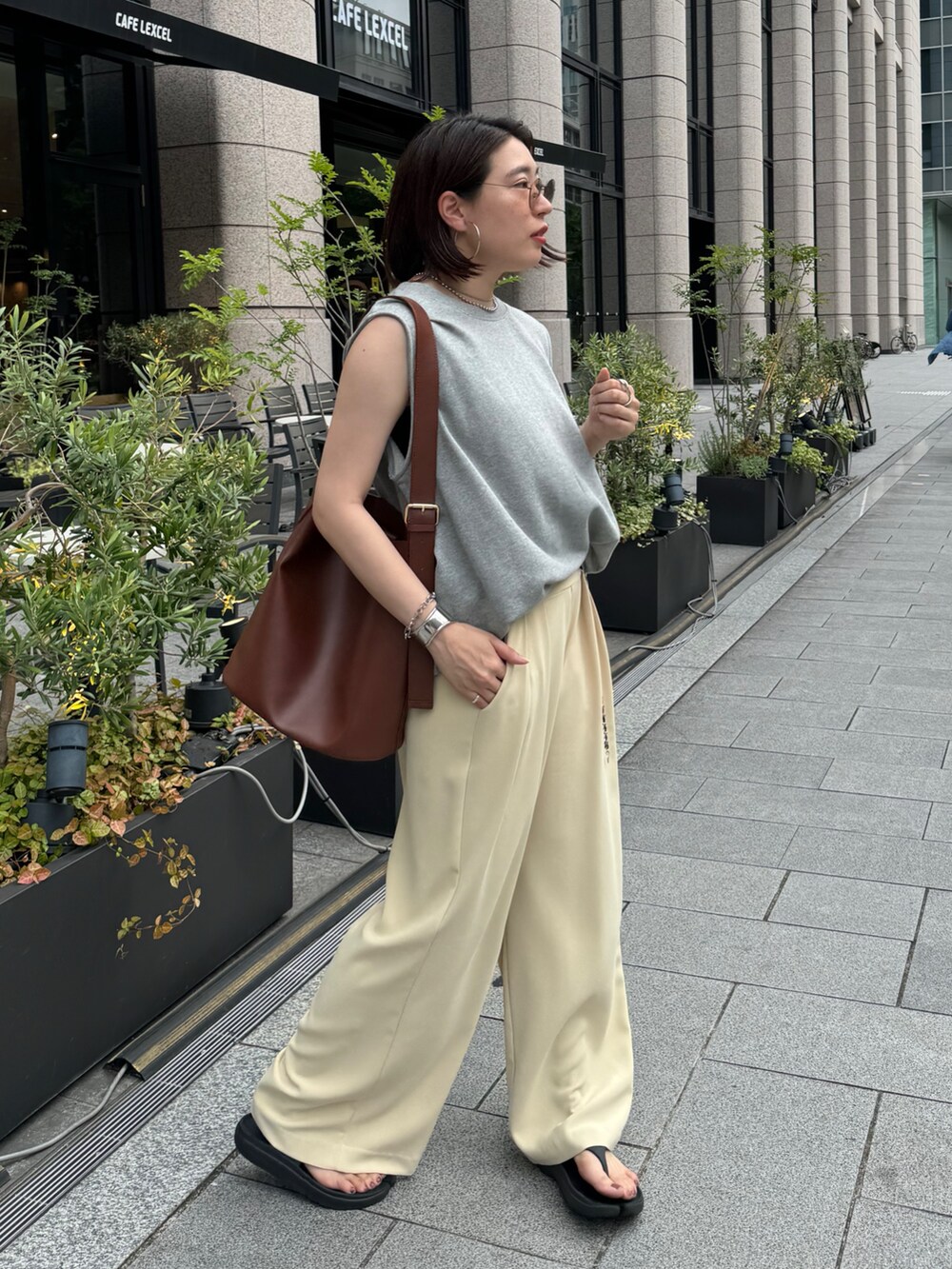 イエロー系のスラックス、グレー系のスウェット、シルバー系のベルトを着用したレディースの夏コーディネートの3枚目の写真