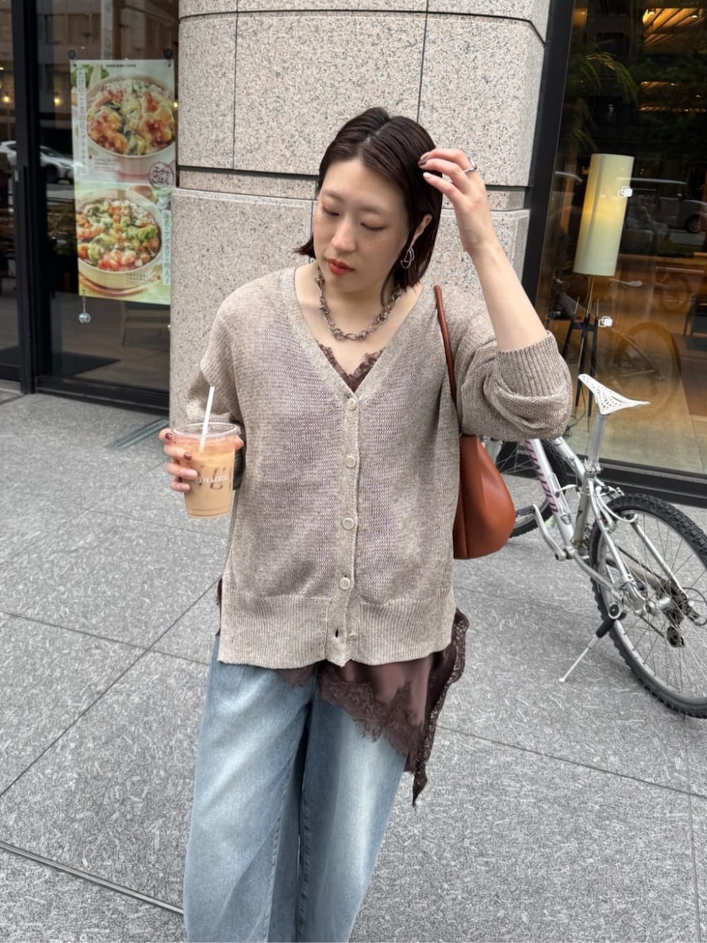 ブルー系のデニムパンツ、ブラウン系のキャミソール、ベージュ系のカーディガン/ボレロを着用したレディースの春コーディネートの4枚目の写真