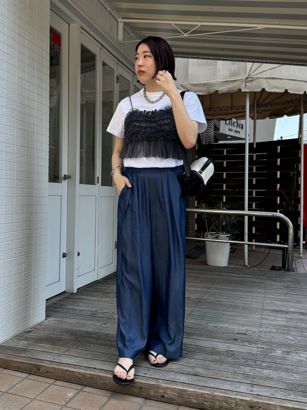 ブルー系のデニムパンツ、ホワイト系のTシャツ/カットソー、グレー系のキャミソールを着用したレディースの夏コーディネートの3枚目の写真