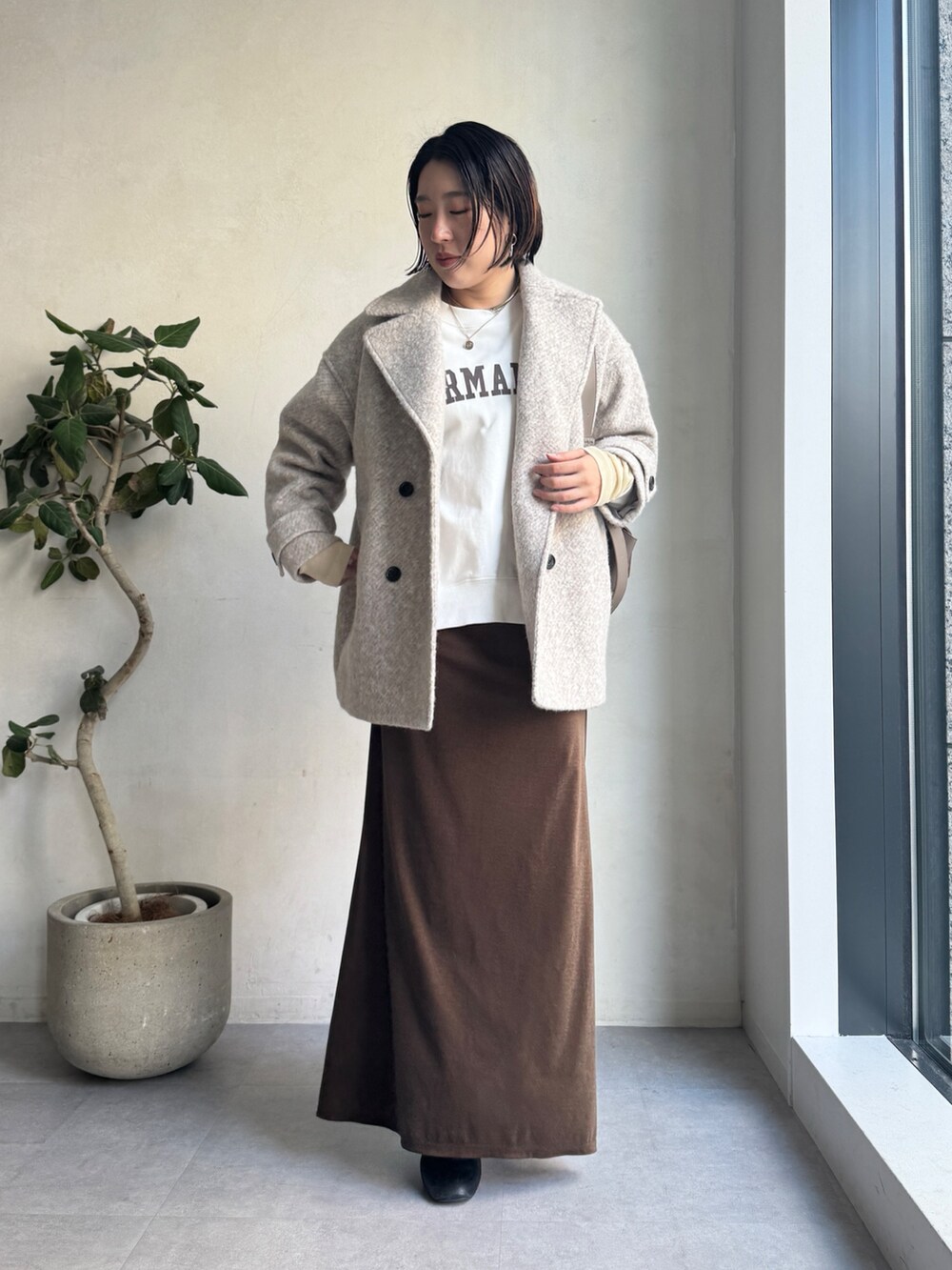 ベージュ系のその他アウター、ブラウン系のスカート、ホワイト系のTシャツ/カットソーを着用したレディースの冬コーディネートの3枚目の写真