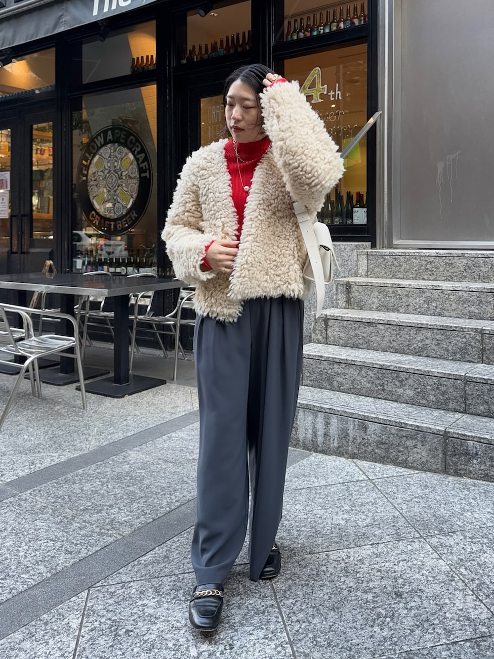 グレー系のスラックス、ホワイト系のショルダーバッグ、ベージュ系のカーディガン/ボレロを着用したレディースの冬コーディネートの2枚目の写真