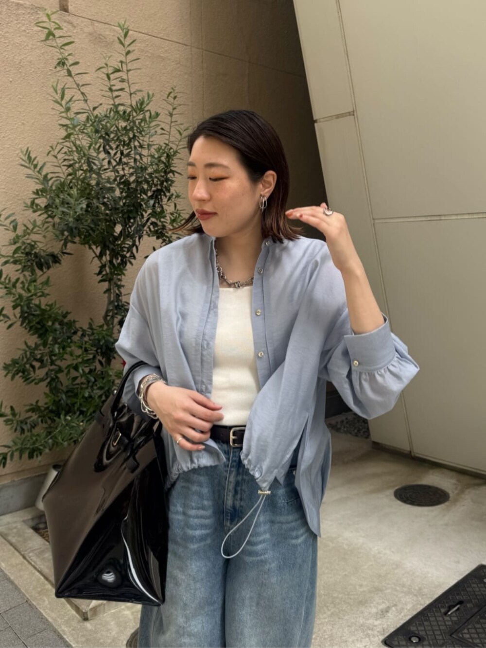 ホワイト系のタンクトップ、ブラック系のショルダーバッグ、ブルー系のデニムパンツを着用したレディースの春コーディネートの5枚目の写真