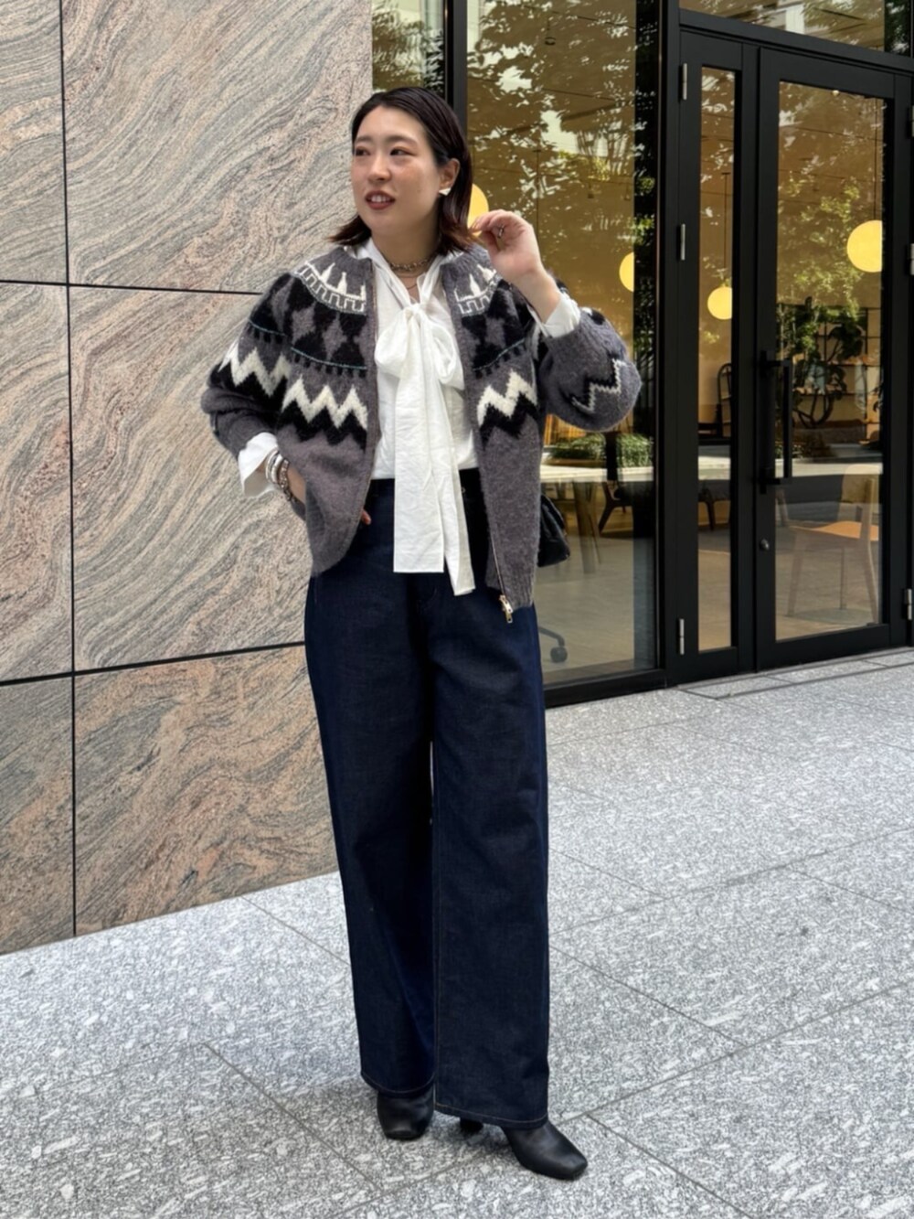 ブラック系のショルダーバッグ、ブルー系のデニムパンツ、ホワイト系のシャツ/ブラウスを着用したレディースの秋コーディネートの3枚目の写真