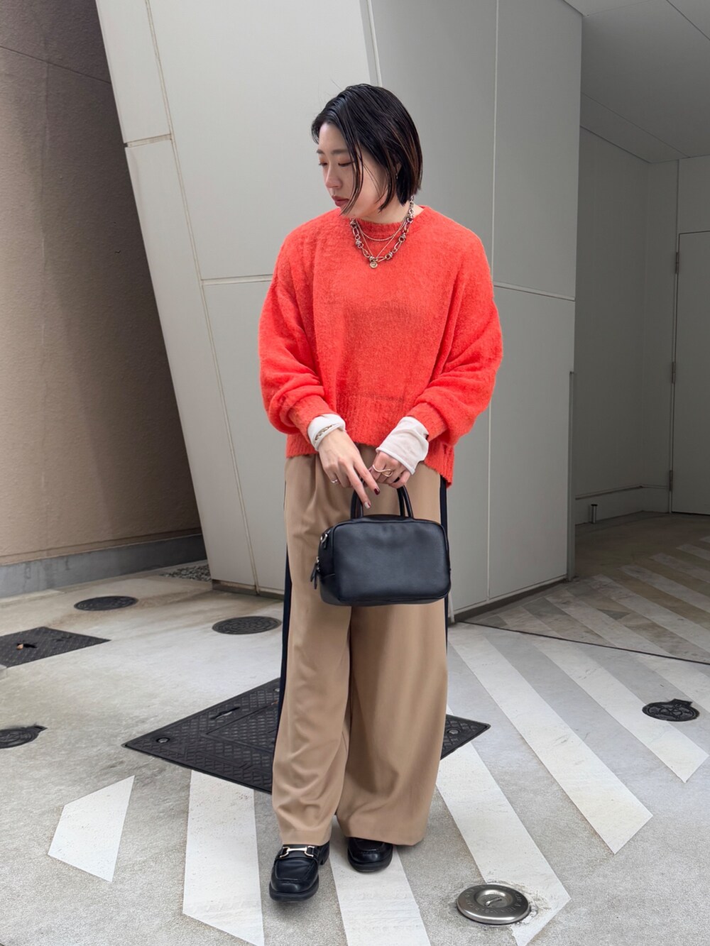 ベージュ系のその他パンツ、ホワイト系のその他アウター、オレンジ系のニット/セーターを着用したレディースの冬コーディネートの6枚目の写真