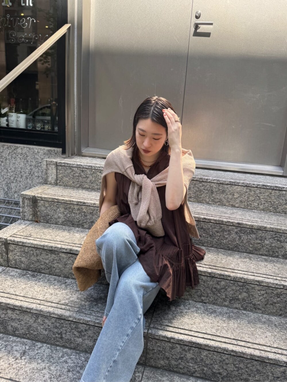 ブルー系のデニムパンツ、ベージュ系のカーディガン/ボレロ、ブラウン系のシャツ/ブラウスを着用したレディースの春コーディネートの6枚目の写真