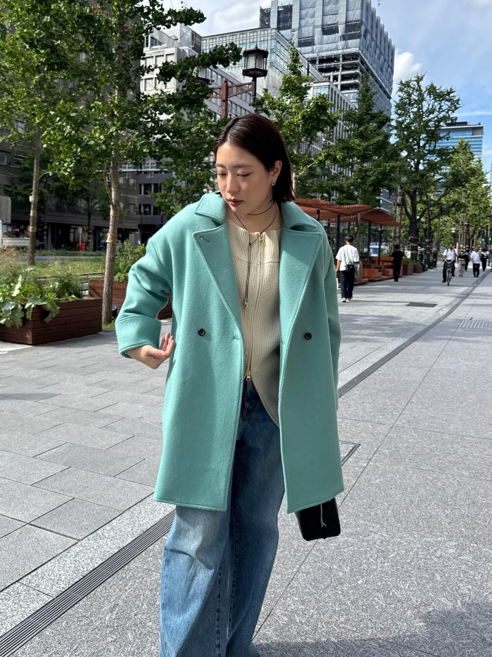 ベージュ系のニット/セーター、グリーン系のその他アウター、ブルー系のデニムパンツを着用したレディースの秋コーディネートの7枚目の写真