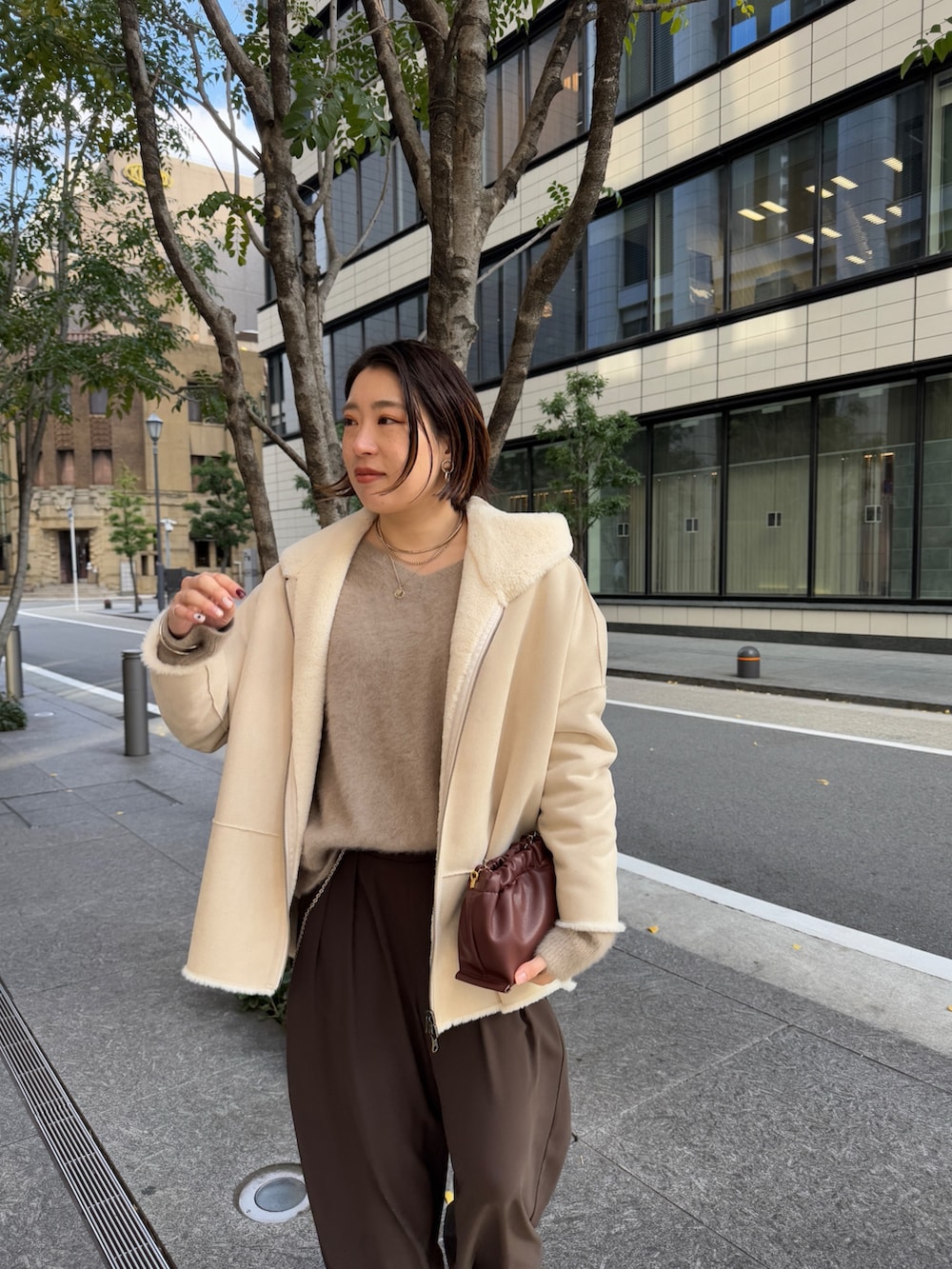 ブラウン系のスラックス、ブラウン系のニット/セーター、ホワイト系のその他アウターを着用したレディースの冬コーディネートの5枚目の写真