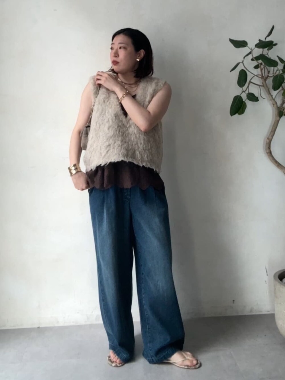 グレー系のショルダーバッグ、ベージュ系のニット/セーター、ブルー系のデニムパンツを着用したレディースの秋コーディネートの4枚目の写真